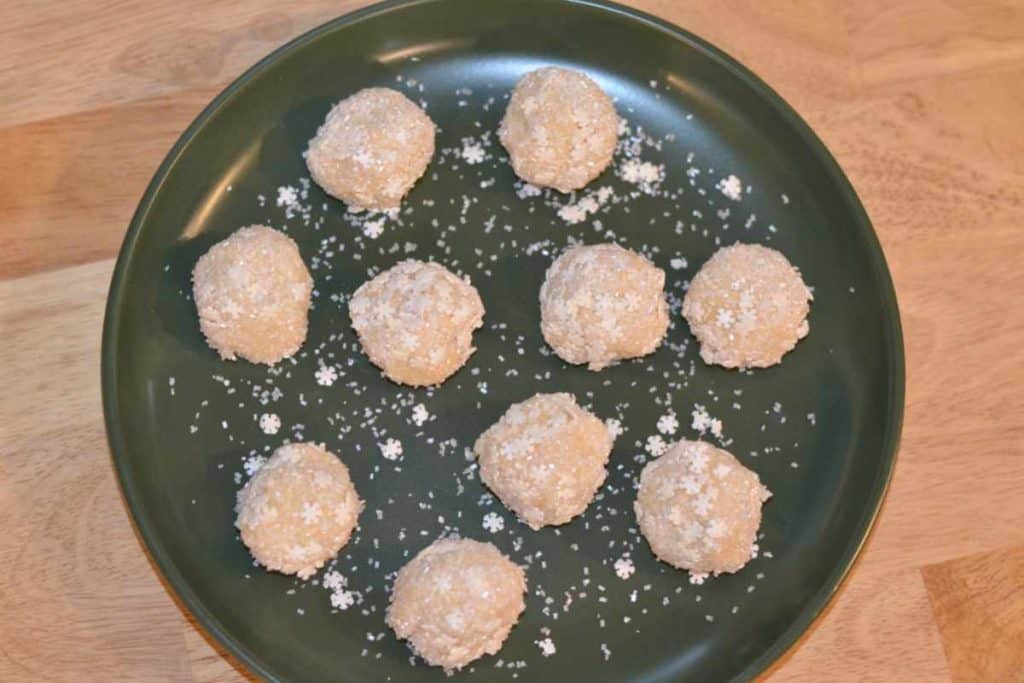 Sugar cookie dough bites rolled in sanding sugar and sprinkles in a green plate from above