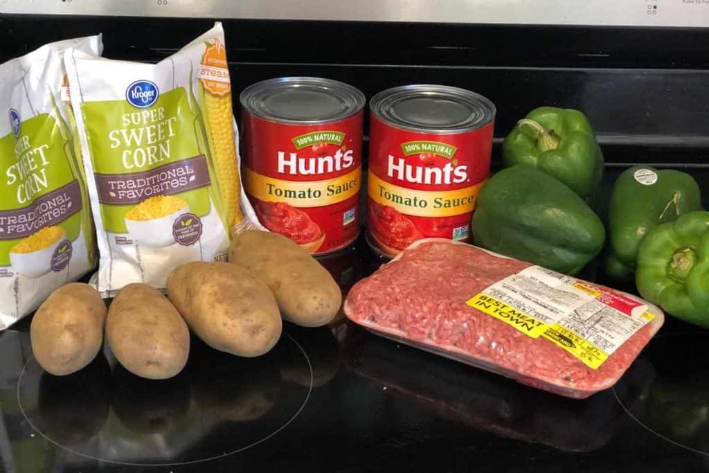 Ingredients for stuffed peppers including green peppers, lean ground beef, tomato sauce, potatoes and frozen corn.