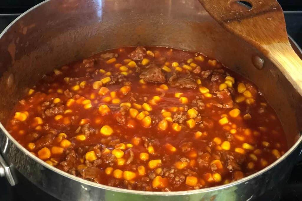 Stuffed pepper filling in a pot simmering, with beef, corn and tomato sauce.