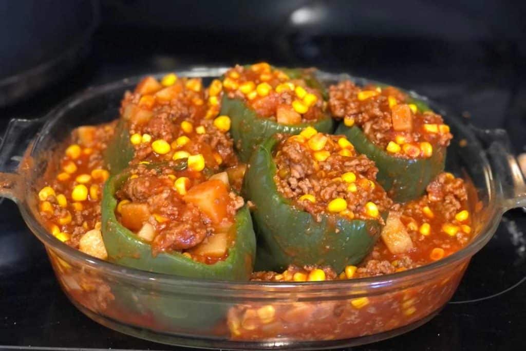 Stuffed peppers ready to go into the oven in a glass casserole dish