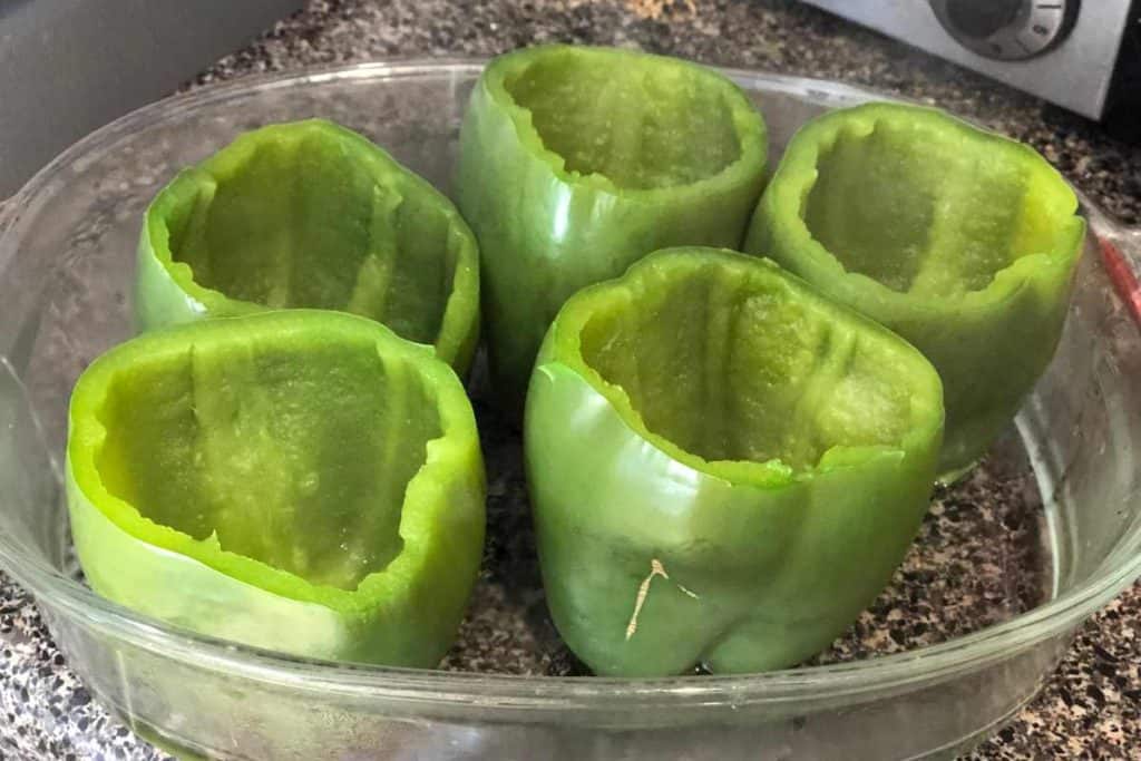 Green peppers that have been pre-cooked and are in a glass baking dish ready to be "stuffed!"