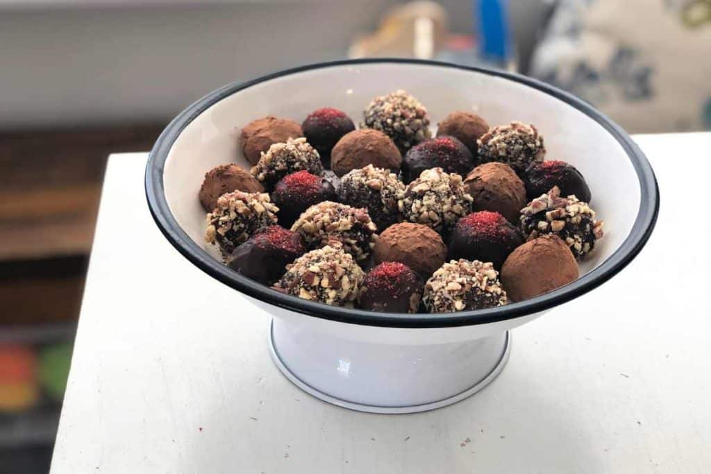 Top view of a cake tray holding various chocolate truffles of various flavors and toppings including pecans, cocoa and chocolate.