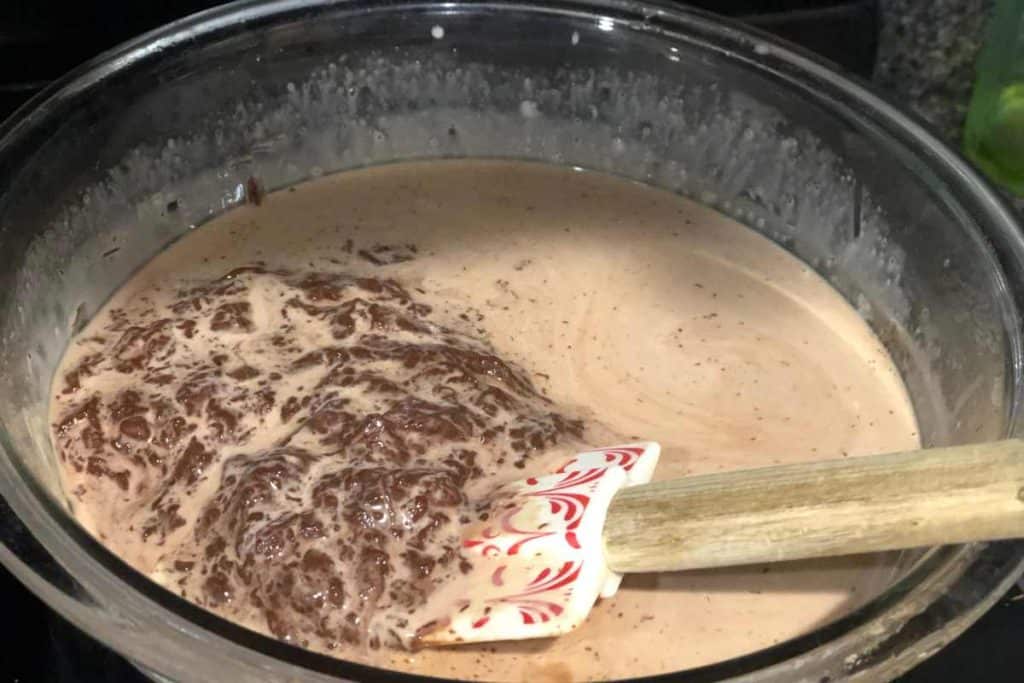 Warm cream with chocolate chips in a bowl with a spatula