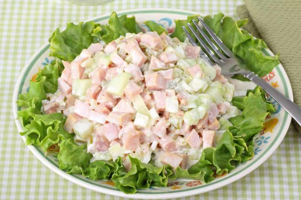 Ham salad scoop on a bed of lettuce on a plate with a fork