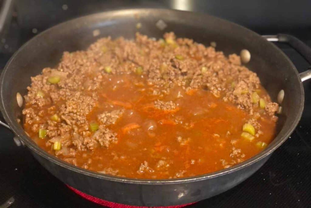 Sloppy Joe recipe simmering on the stove and cooking down the sauce in a large skillet