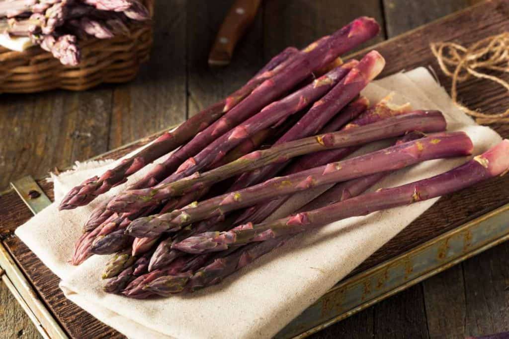 Bundle of purple asparagus on a wooden board