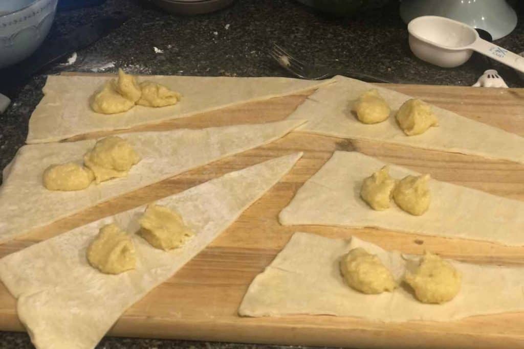 Homemade Almond paste on the puff pastry triangles ready to be spread out and rolled up next