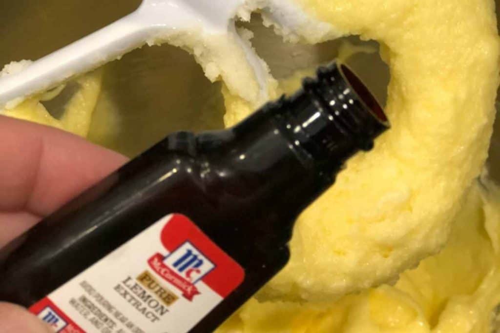 Lemon extract bottle being poured into the lemon pound cake batter.
