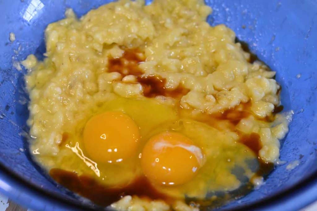 Eggs and vanilla extract on top of mashed bananas for banana bread batter