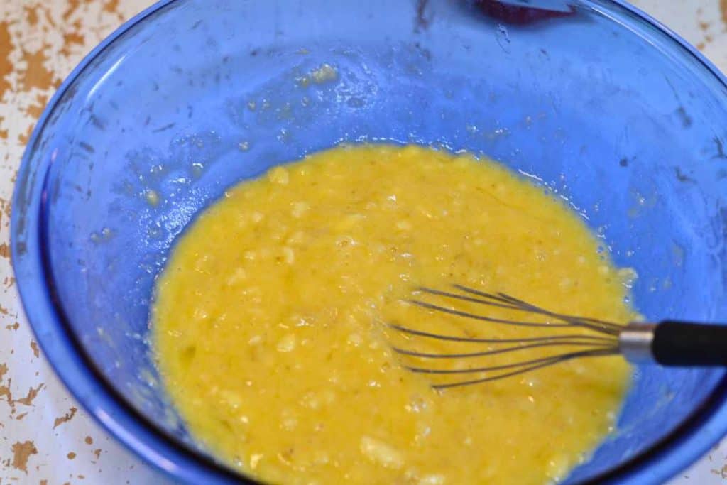 Banana bread batter with all the wet ingredients mixed together in a blue bowl