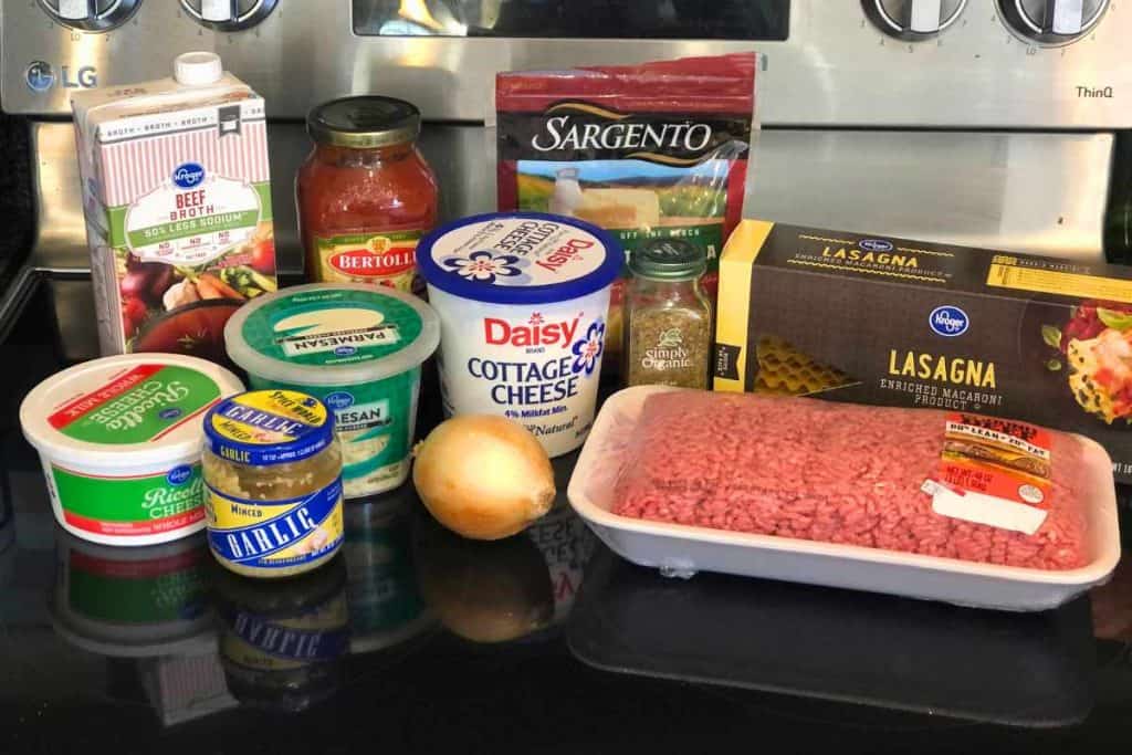Lasagna soup ingredients including ground beef, lasagna noodles, Italian seasoning, mozzerella cheese, onion, cottage cheese, marinara, parmesan cheese, garlic, ricotta cheese and beef broth