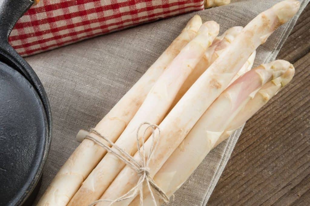 White bundle of asparagus on a wooden table and linen napkin