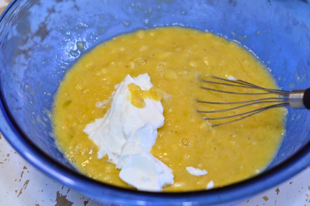 Greek Yogurt sitting on top of banana bread batter ready to be mixed in with the wire whisk