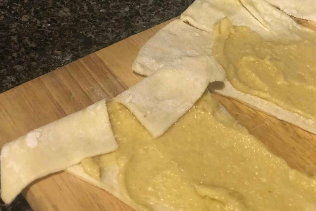Puff pastry covered in almond paste with a small triangle cut out of the very back of the puff pastry to ease rolling up the croissant