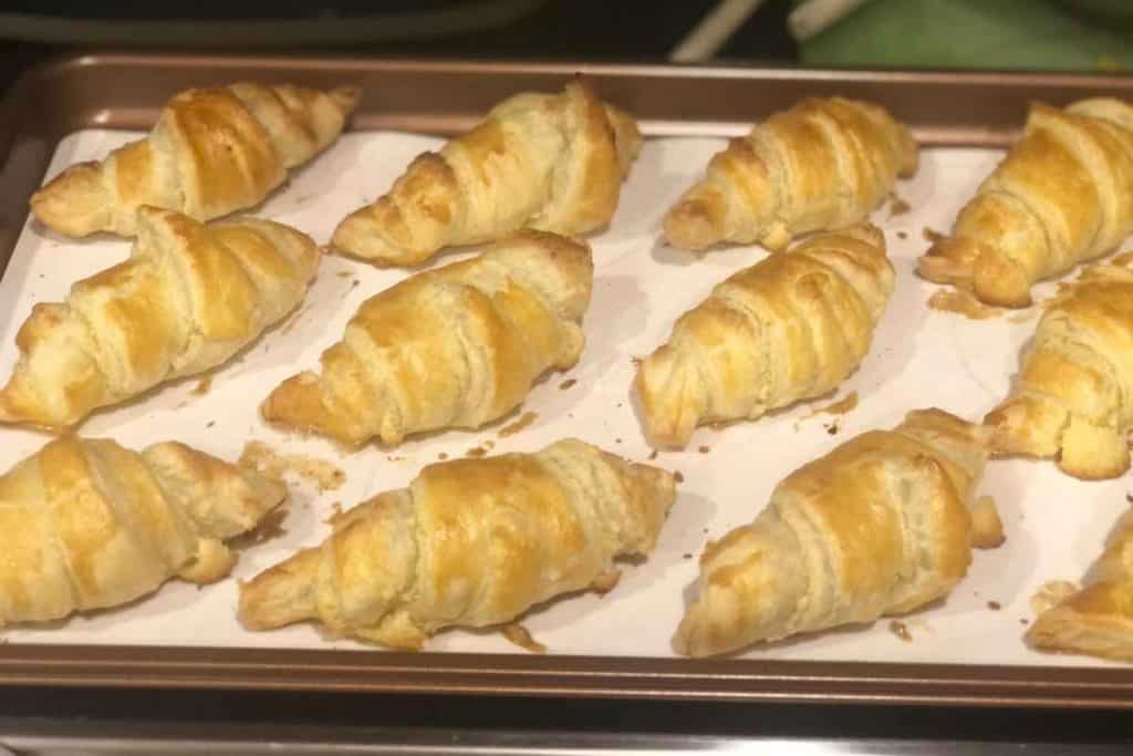 Almond croissants cooked halfway through and are out of the oven for a glaze to be put on before the baking is finished