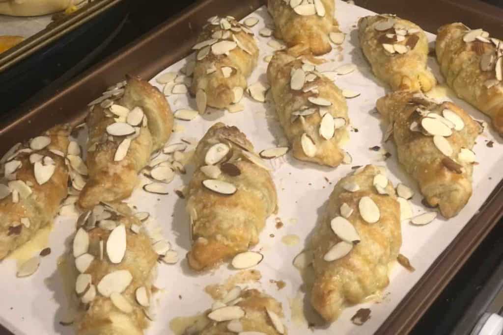 Almond croissants out of the oven and on a parchment lined baking sheet