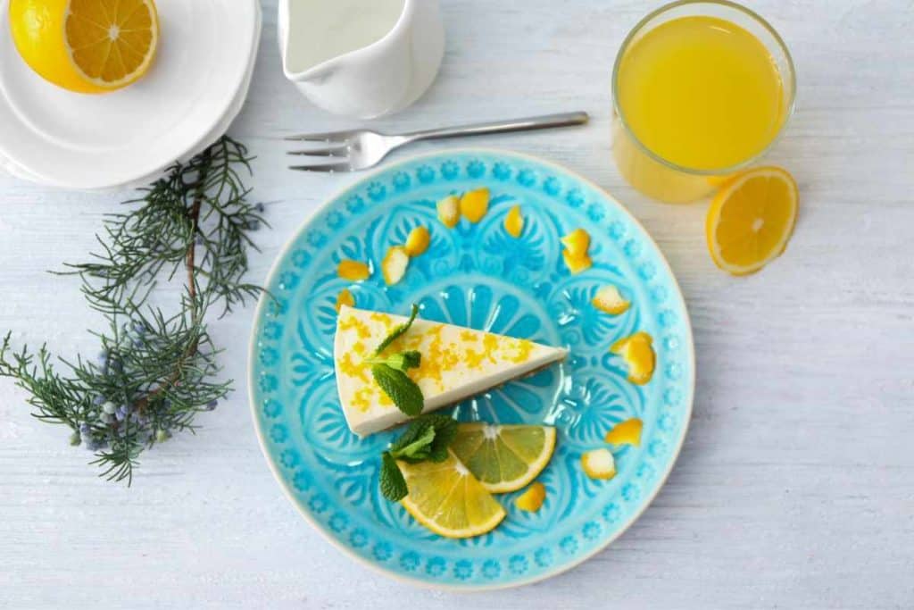Slice of no-bake lemonade cheesecake on a blue plate on a white wooden table