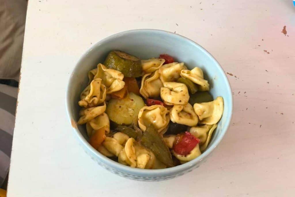 Roasted Cheese tortelleni salad in a blue bowl on a white table
