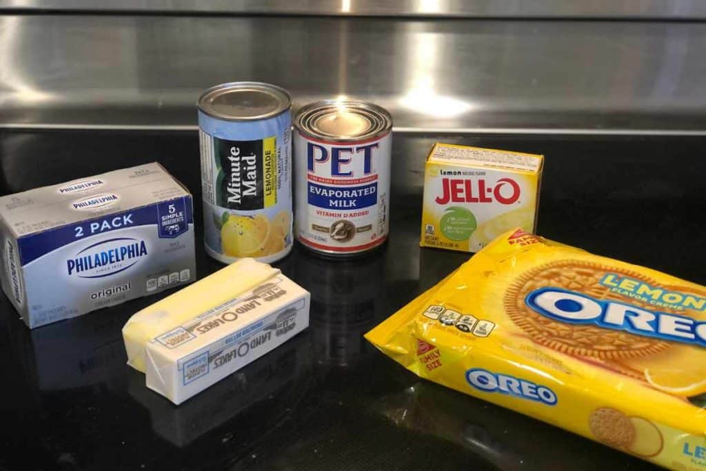 Ingredients for No-Bake Lemonade Cheesecake including lemon Oreo cookies, unsalted butter, lemon jello, evaporated milk, lemonade concentrate, and cream cheese