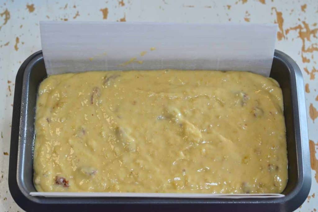 Banana bread batter in a loaf pan lined with parchment paper waiting to go into the oven.