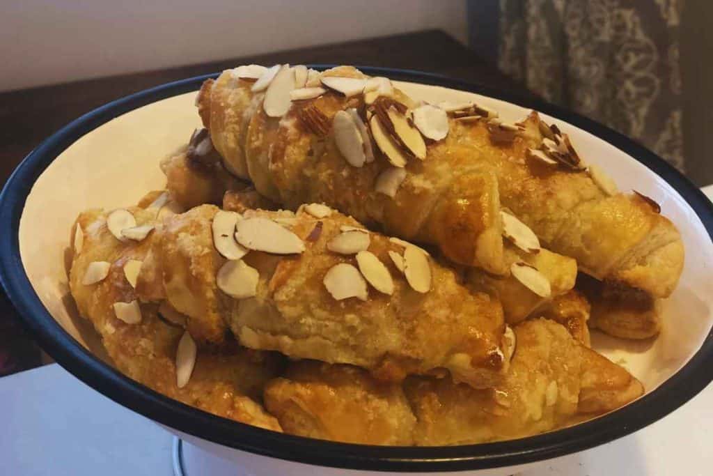 White cake stand holding fresh almond croissants