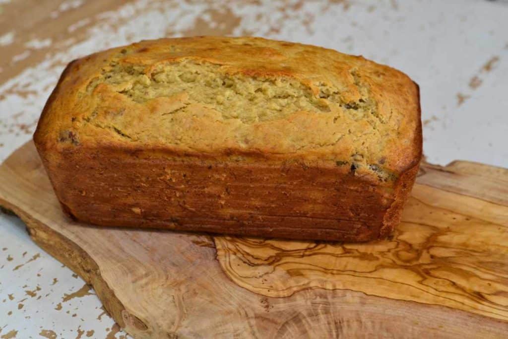 Loaf of banana bread sitting on a wooden cutting board