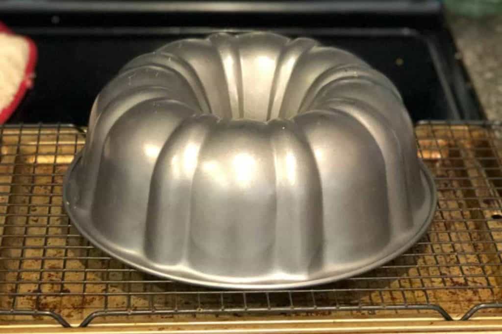 Upside down bundt cake pan on a cooling rack with lemon pound cake inside it