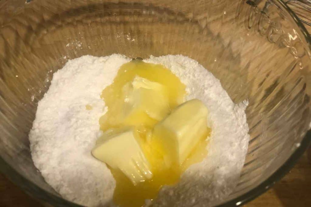 Sugar and melted butter in a glass mixing bowl