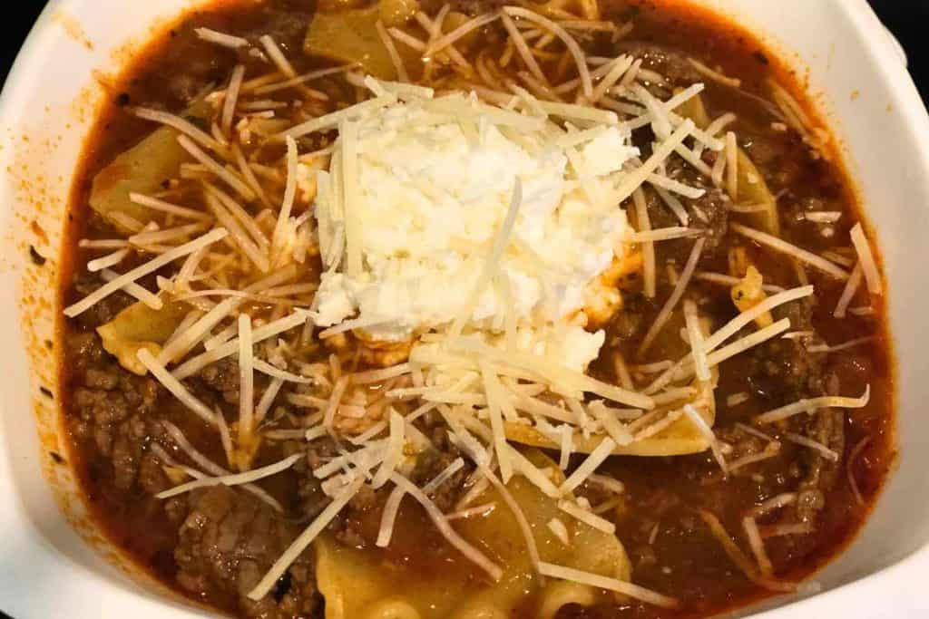 Finished lasagna soup with parmesan cheese on top and a dollop of the cheese mixture for garnish