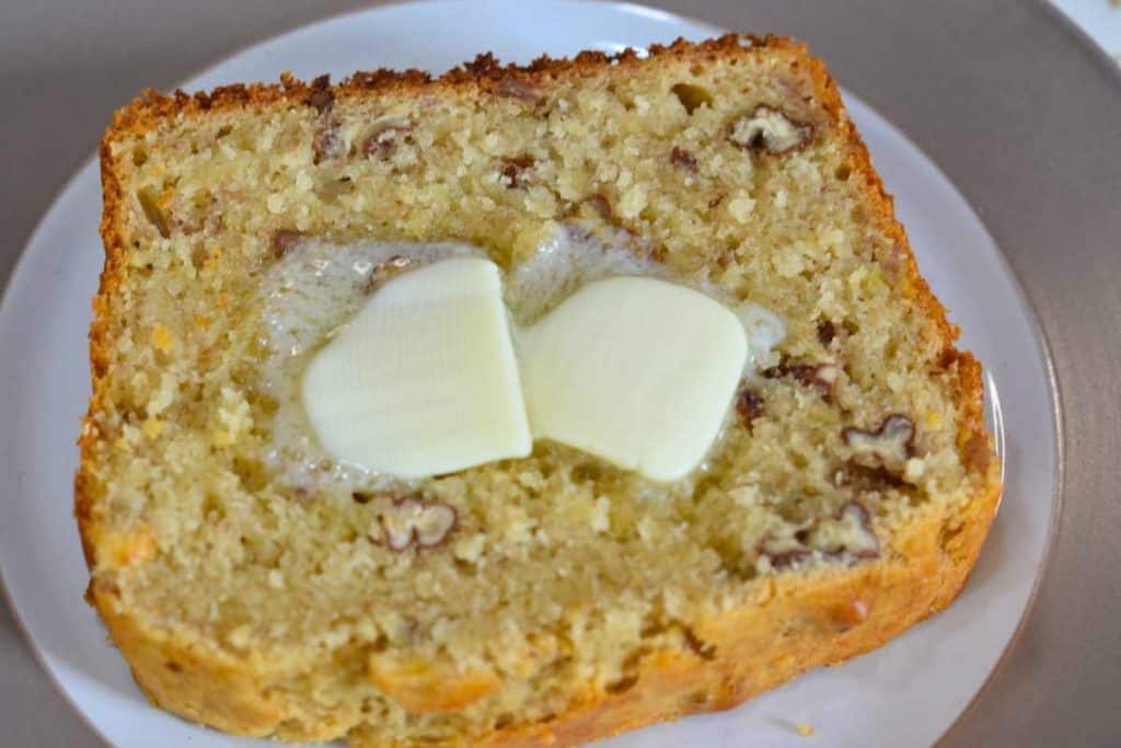 Slice of banana bread with two pats of butter on top melting.
