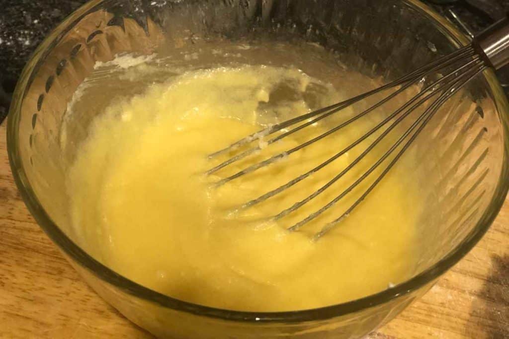 A mix of homemade almond paste in a glass bowl with a whisk