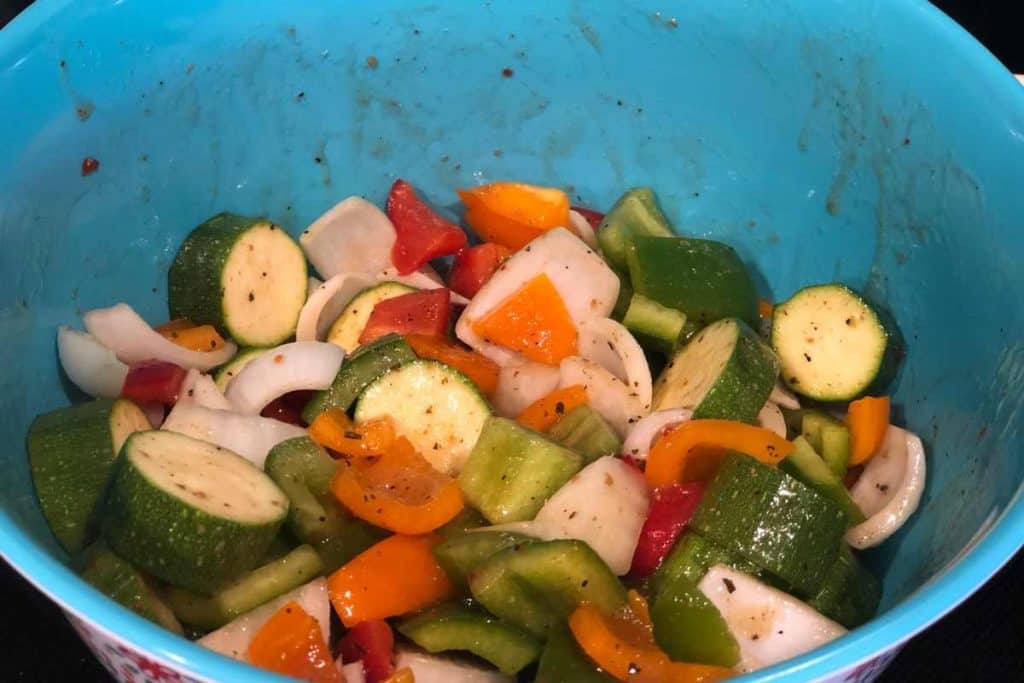 Chunky cut up vegetables with Italian dressing poured on top and mixed up in the bowl