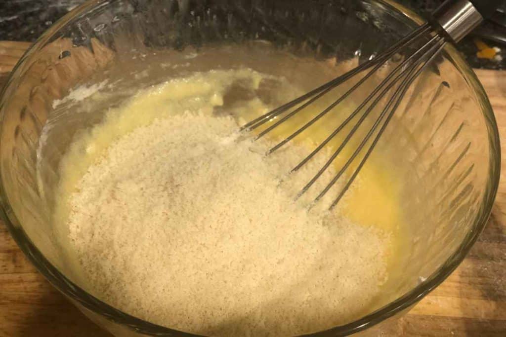 a bowl of homemade almond paste ingredients with almond flour added on top to mix in