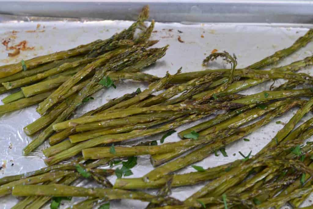 Roasted asparagus on an aluminum foil lined baking sheet that is done and ready to eat