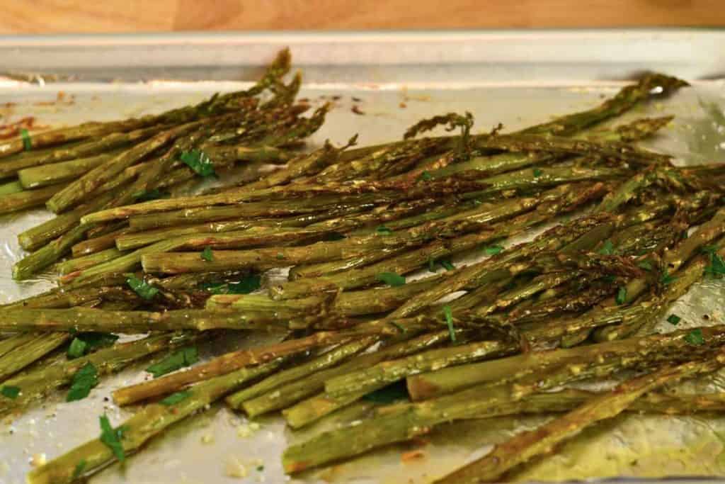 Roasted asparagus sprinkled with parsley after it's come out fo the oven and is ready to eat
