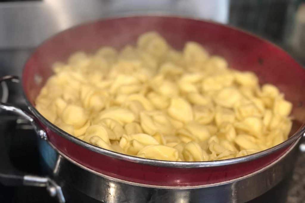 Cheese tortellini in a red strainer