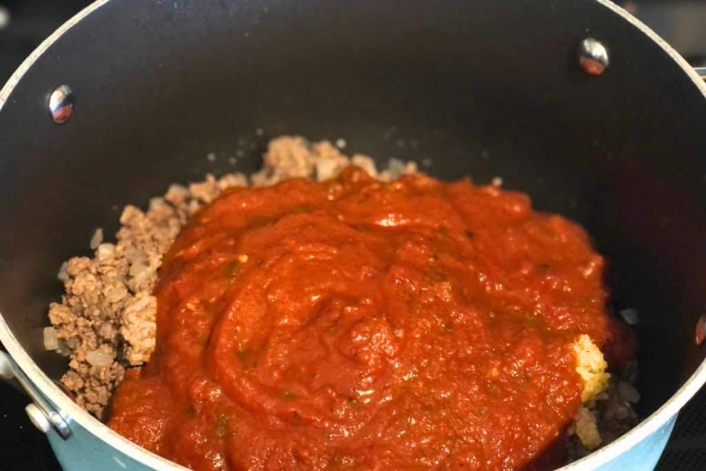 Marinara sauce poured over the cooked ground beef