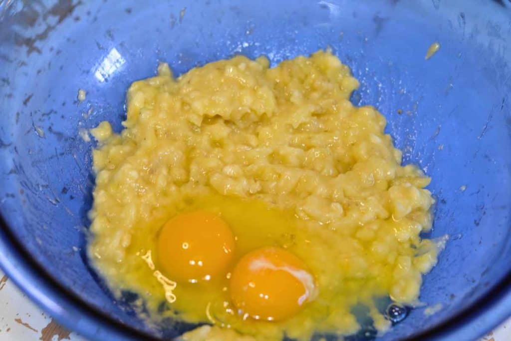 Eggs on top of mashed bananas as the beginning of a banana bread recipe