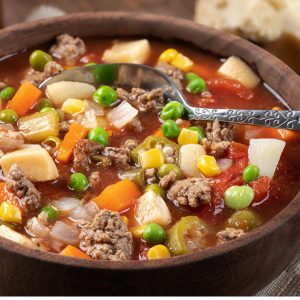 Wooden soup bowl filled with Easy and Quick Instant Pot Vegetable Beef Soup Recipe with a silver spoon.