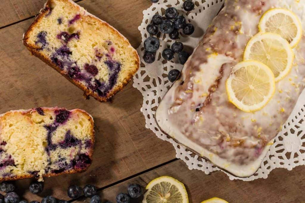 A blueberry lemon loaf cake with glaze and sliced lemons on top looking at it from above
