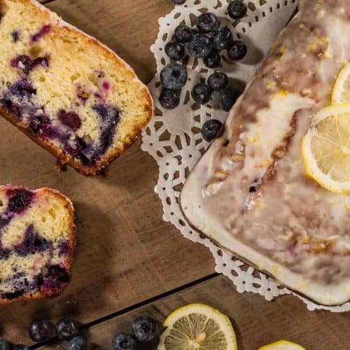 A blueberry lemon loaf cake with glaze and sliced lemons on top looking at it from above