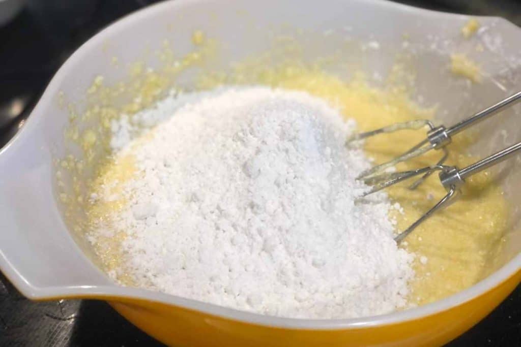 Lemon blueberry Loaf batter with flour on the top with an electric mixer on the side ready to mix the ingredients together