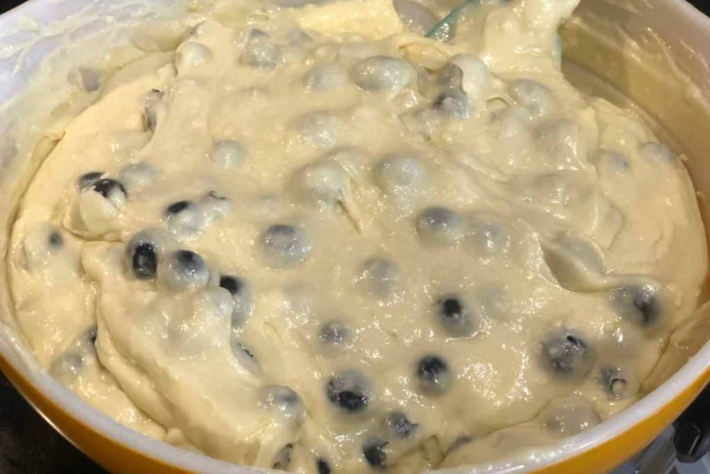 The finished mixture for lemon blueberry loaf cake in an orange mixing bowl