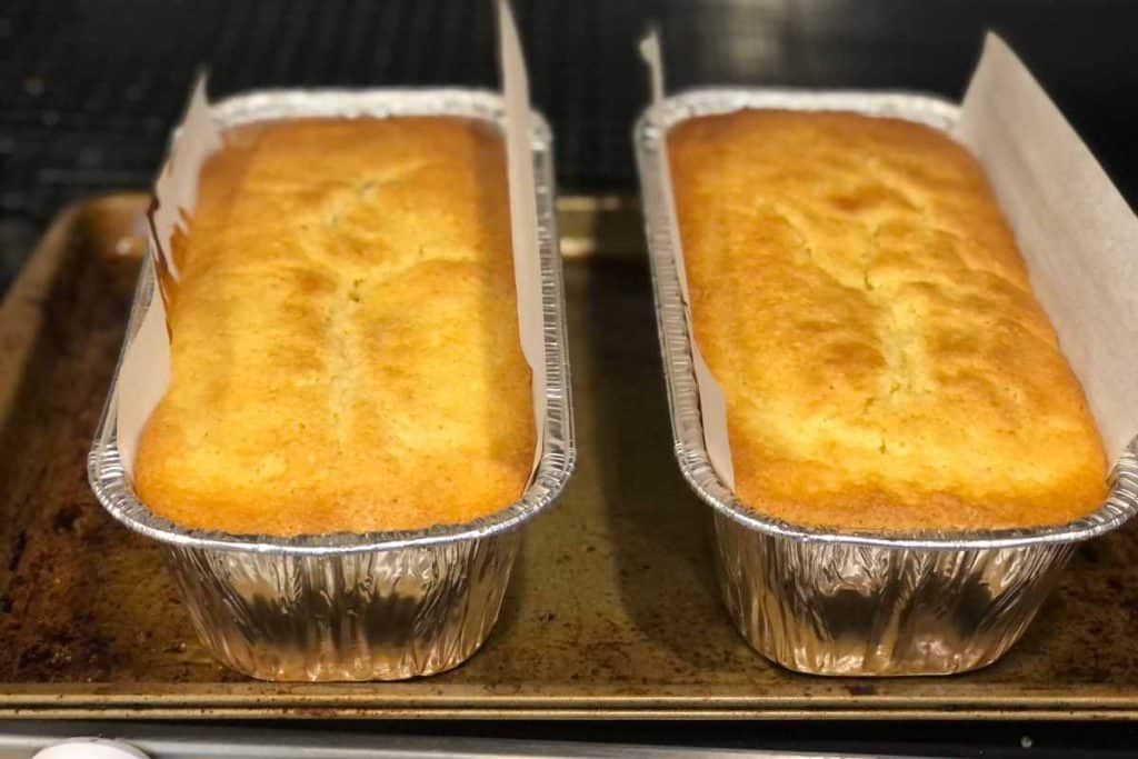 Blueberry Lemon Loaf straight out of the oven waiting to cool off to be removed from pan. The loafs are in aluminum loaf pans with parchment paper for easy removal.