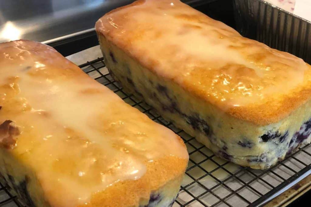 Blueberry Lemon Loaf glazed and cooling on a wire cooling wrack over parchment paper