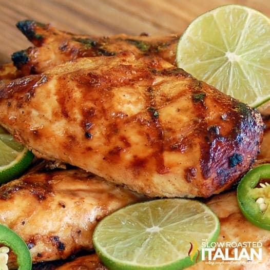 Best Ever Margarita Chicken on a wooden cutting borad with fresh jalepenos and limes for garnish.