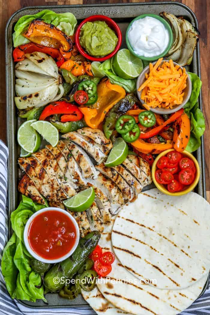 Grilled Chicken Fajitas on a platter with tortillas and condiments for fajitas.