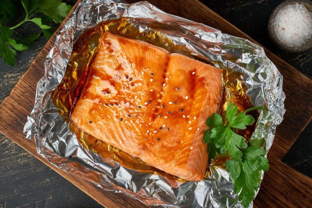 Honey Teriyaki salmon on a cutting board and ready to eat with foil peeled back