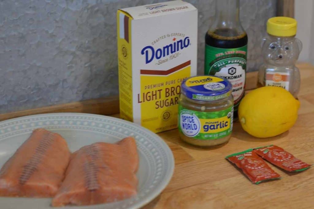 Ingredients for honey teriyaki salmon packets including lemon, honey, Sriacha sauce, garlic, soy sauce, salmon and brown sugar.