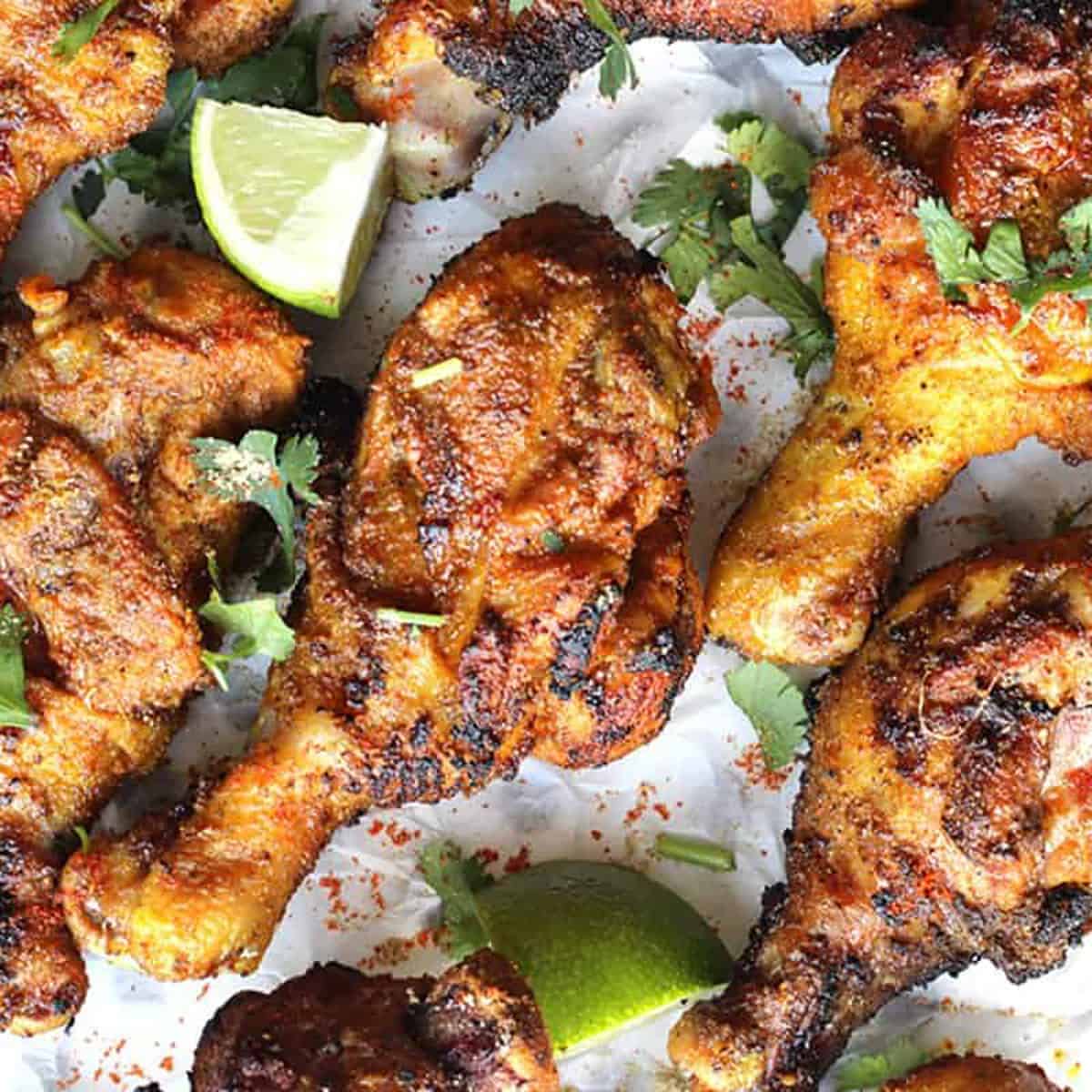 Grilled Tandoori Chicken on parchment paper with lime wedges